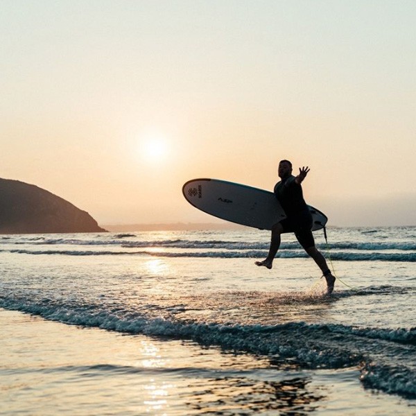 Surfer Running Into The Ocean At Sunset
