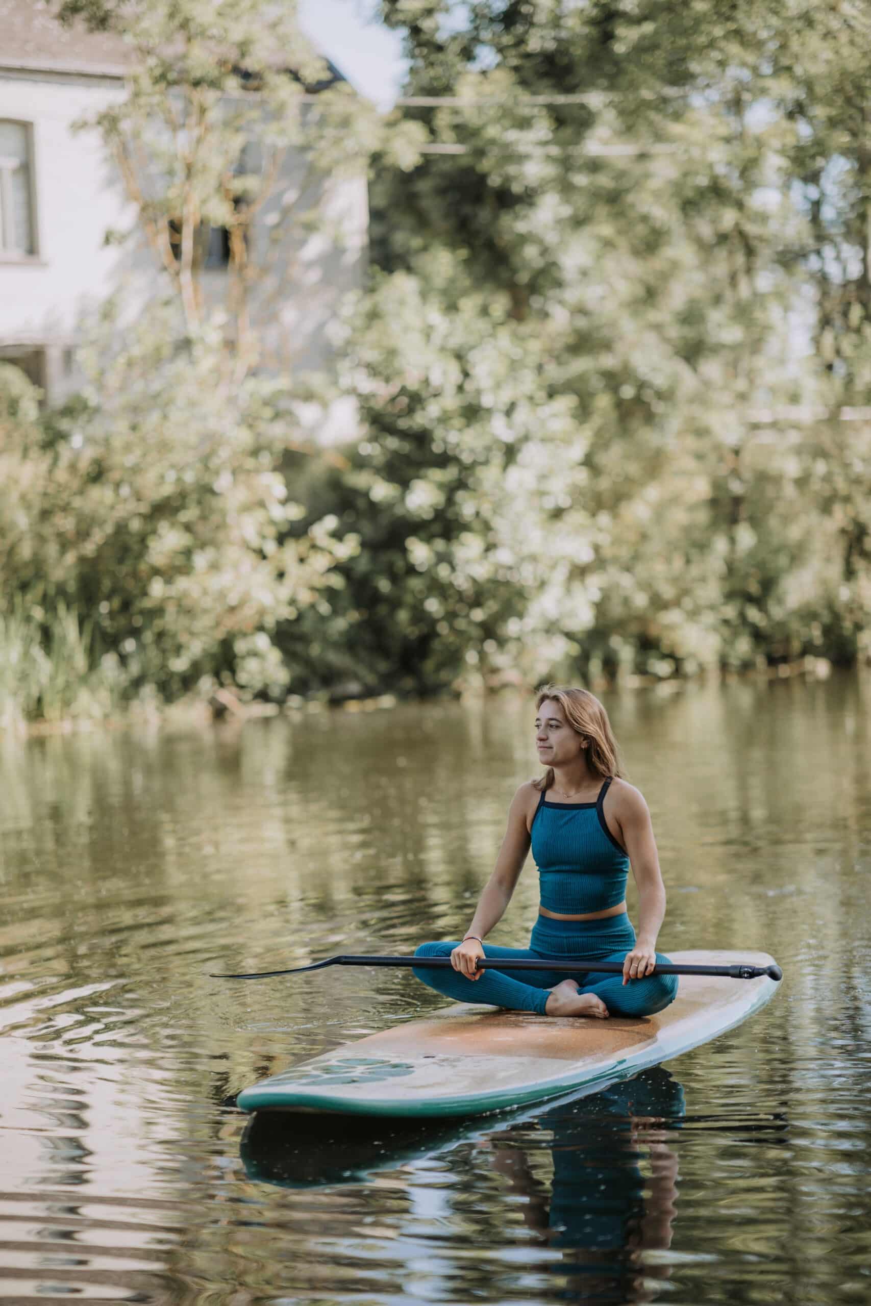 Woman Sitting on Paddle Board in Calm River