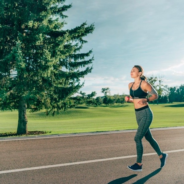 Woman Jogging Outdoors In Sunny Park