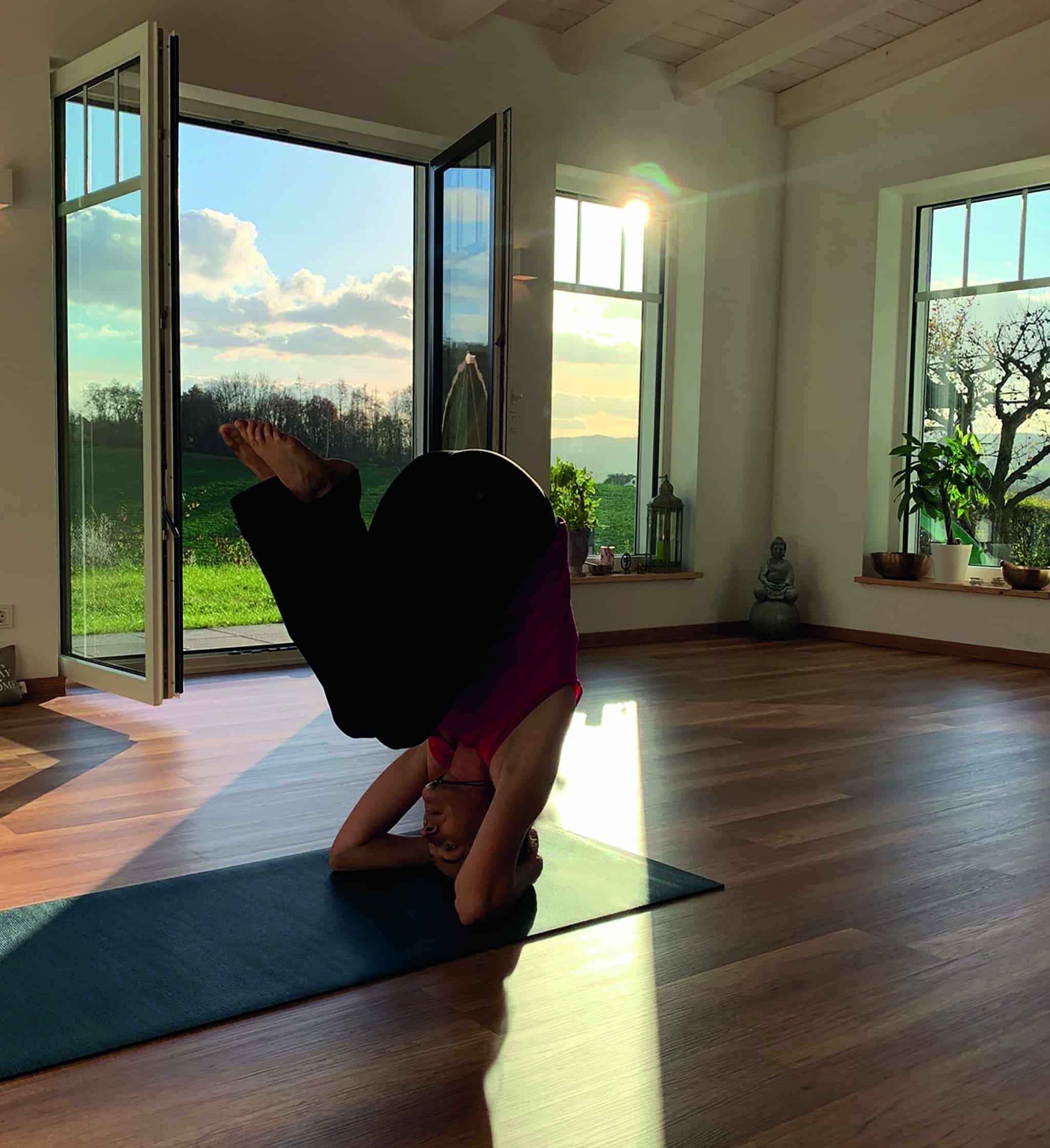 Woman Practicing Headstand In Sunlit Studio