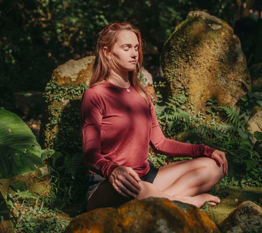 Woman Meditating In Nature Near Rocks