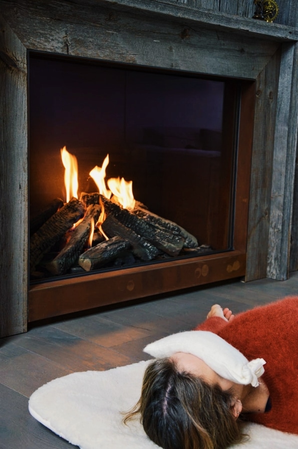 Woman Relaxing By Fireplace On Wool Mat