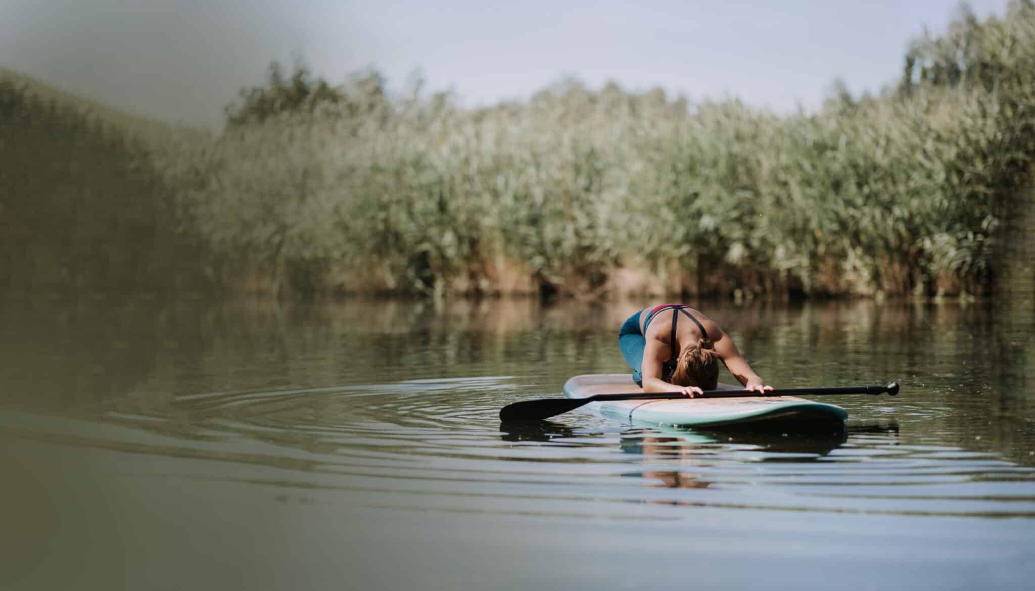 Woman Practicing Yoga On Paddle Board