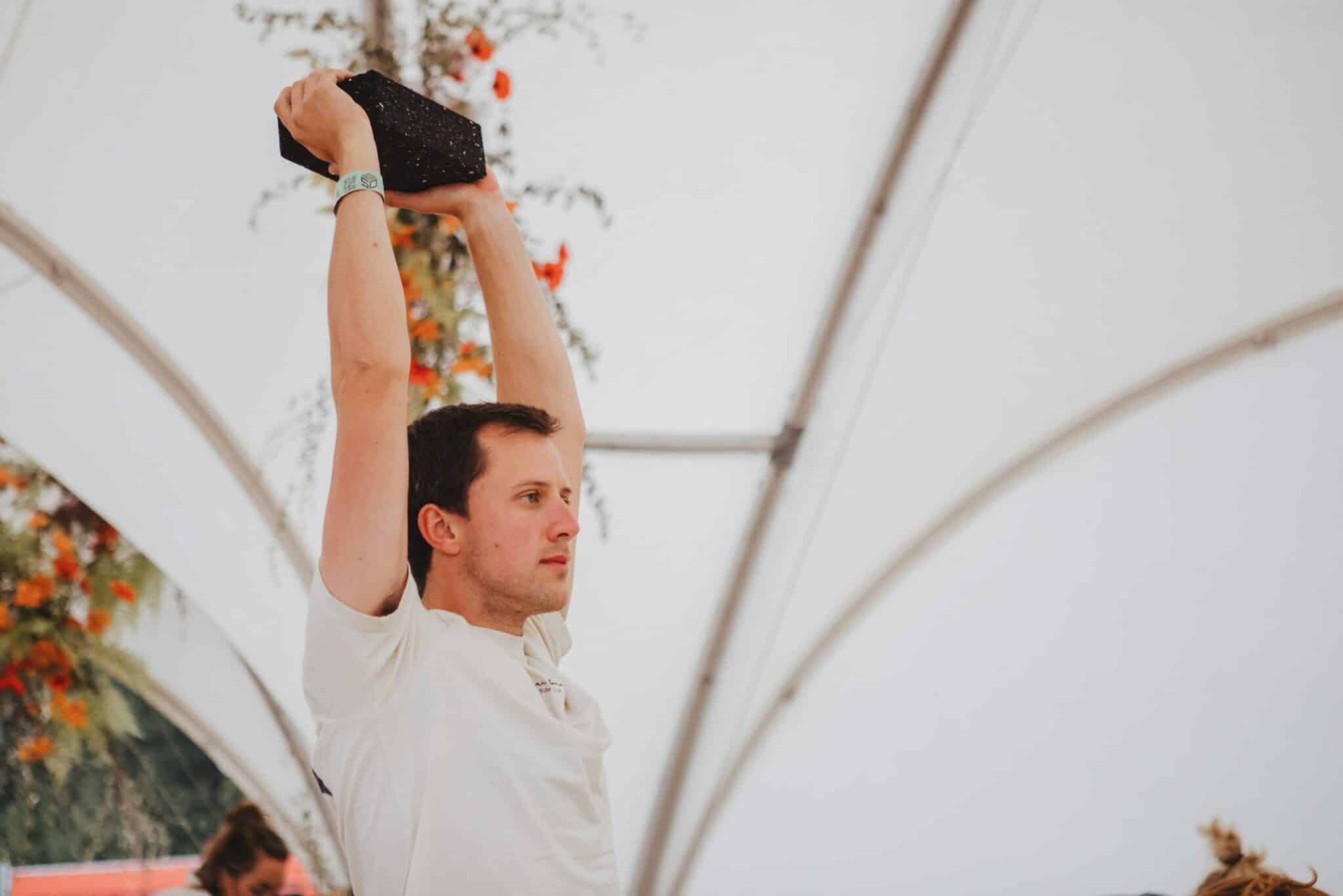 Man Holding Black Yoga Block Overhead