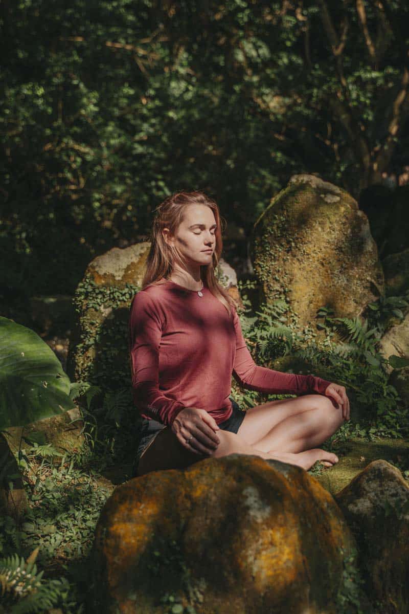 Woman Meditating Outdoors In Lush Garden