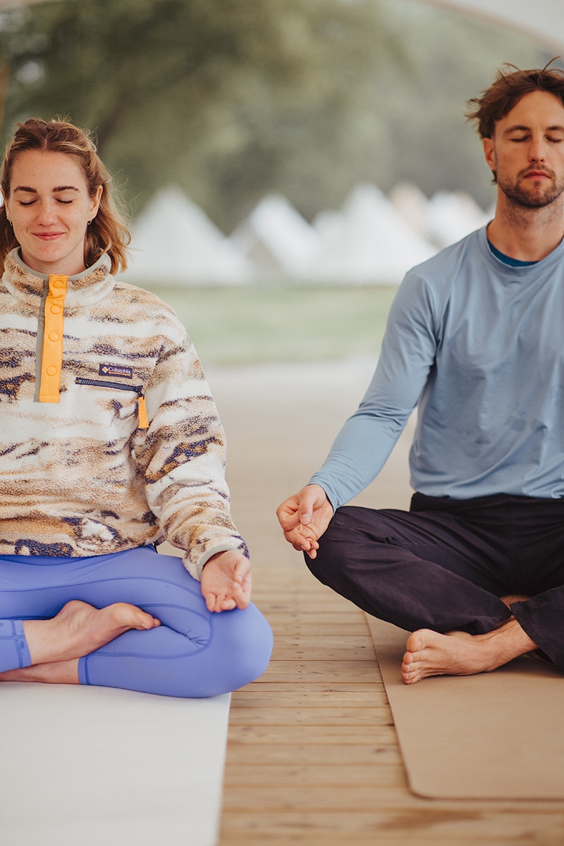 People Practicing Meditation Outdoors On Mats